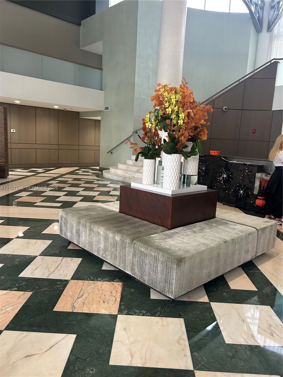 Grand foyer featuring geometric stone flooring in a contrasting diamond pattern, multi-level architectural design, and integrated panel wall detailing