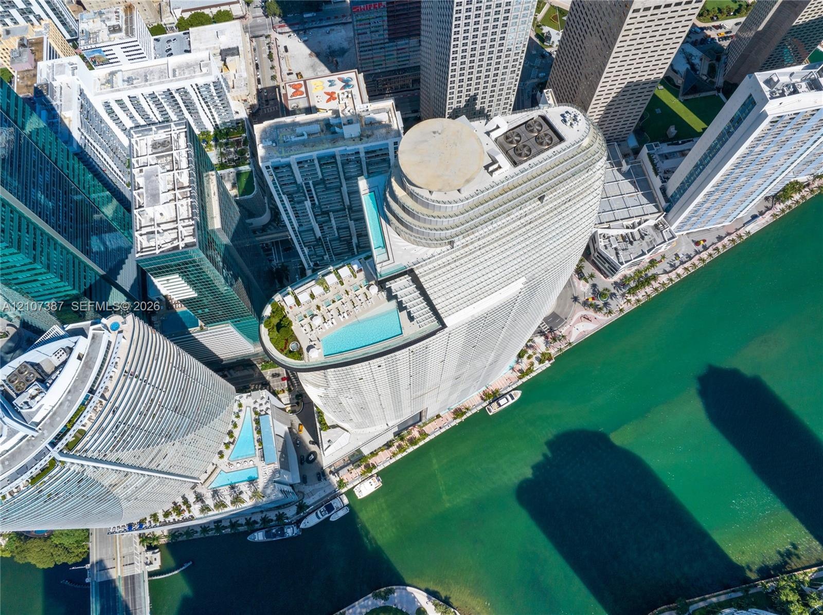 High-rise residential tower featuring a rooftop swimming pool, terrace, and water frontage