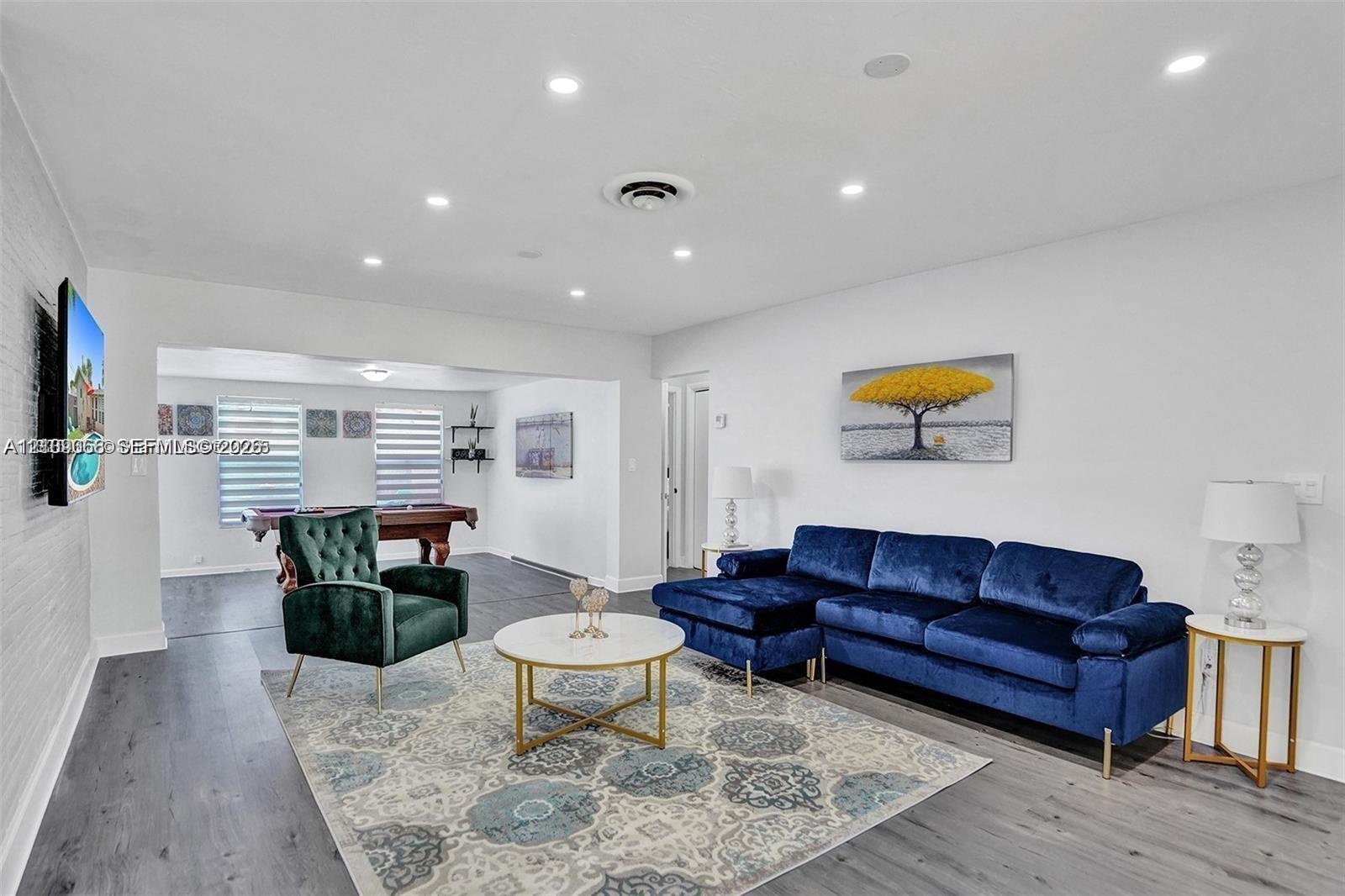 Open-concept interior featuring wood-finish flooring, recessed lighting, and horizontal window blinds
