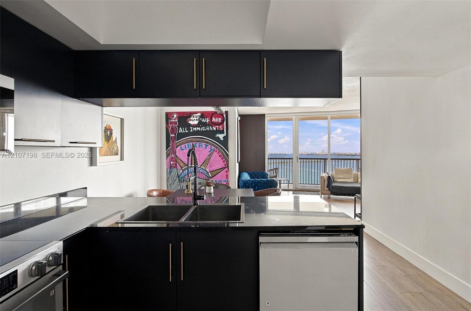 Kitchen featuring matte black cabinetry with brushed gold hardware, stone countertops, double basin undermount sink with a gooseneck faucet, stainless