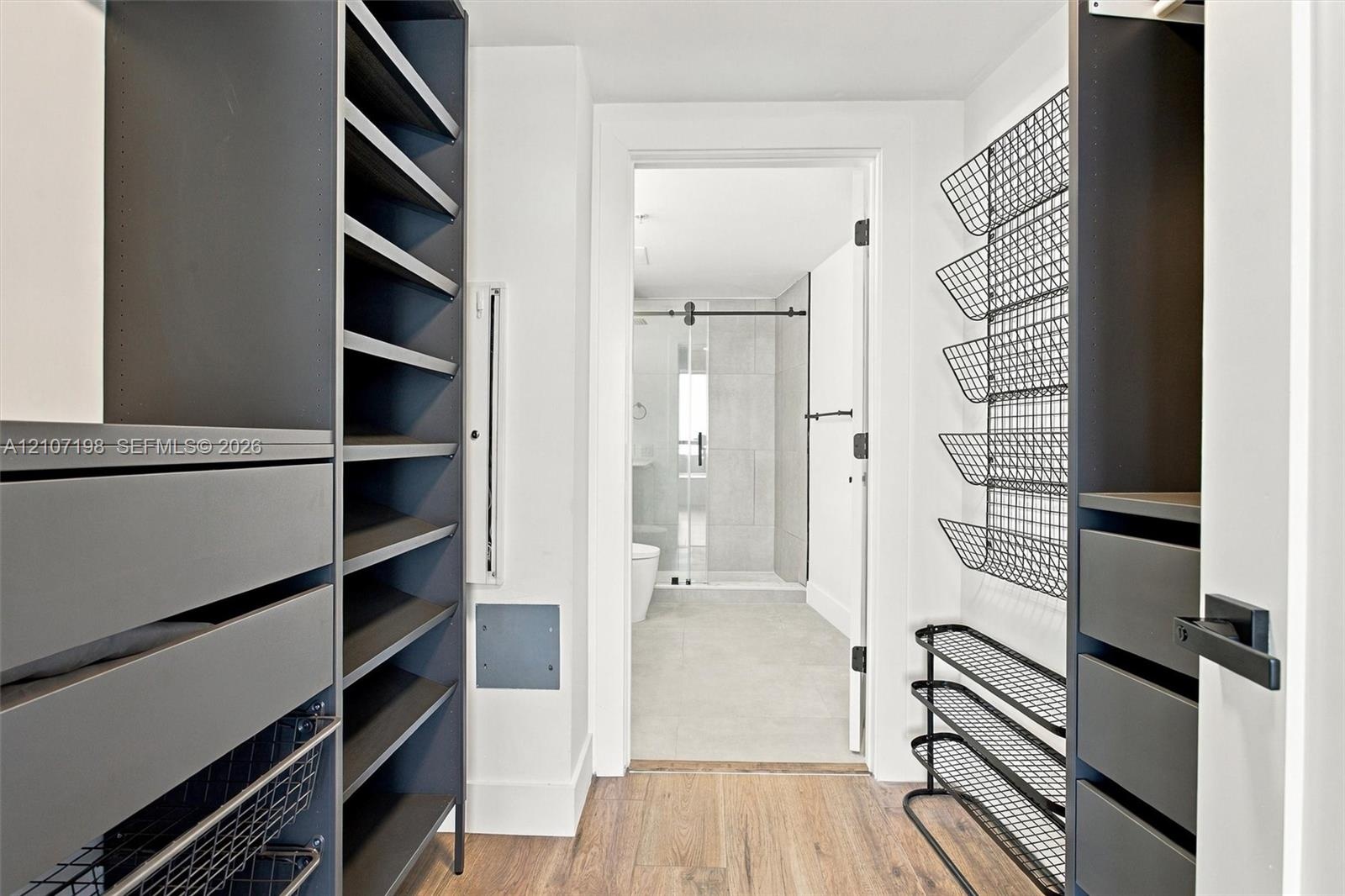 Custom reach-in closet featuring dark-finish built-in cabinetry, integrated drawer banks, adjustable open shelving, and metal wire rack storage with w