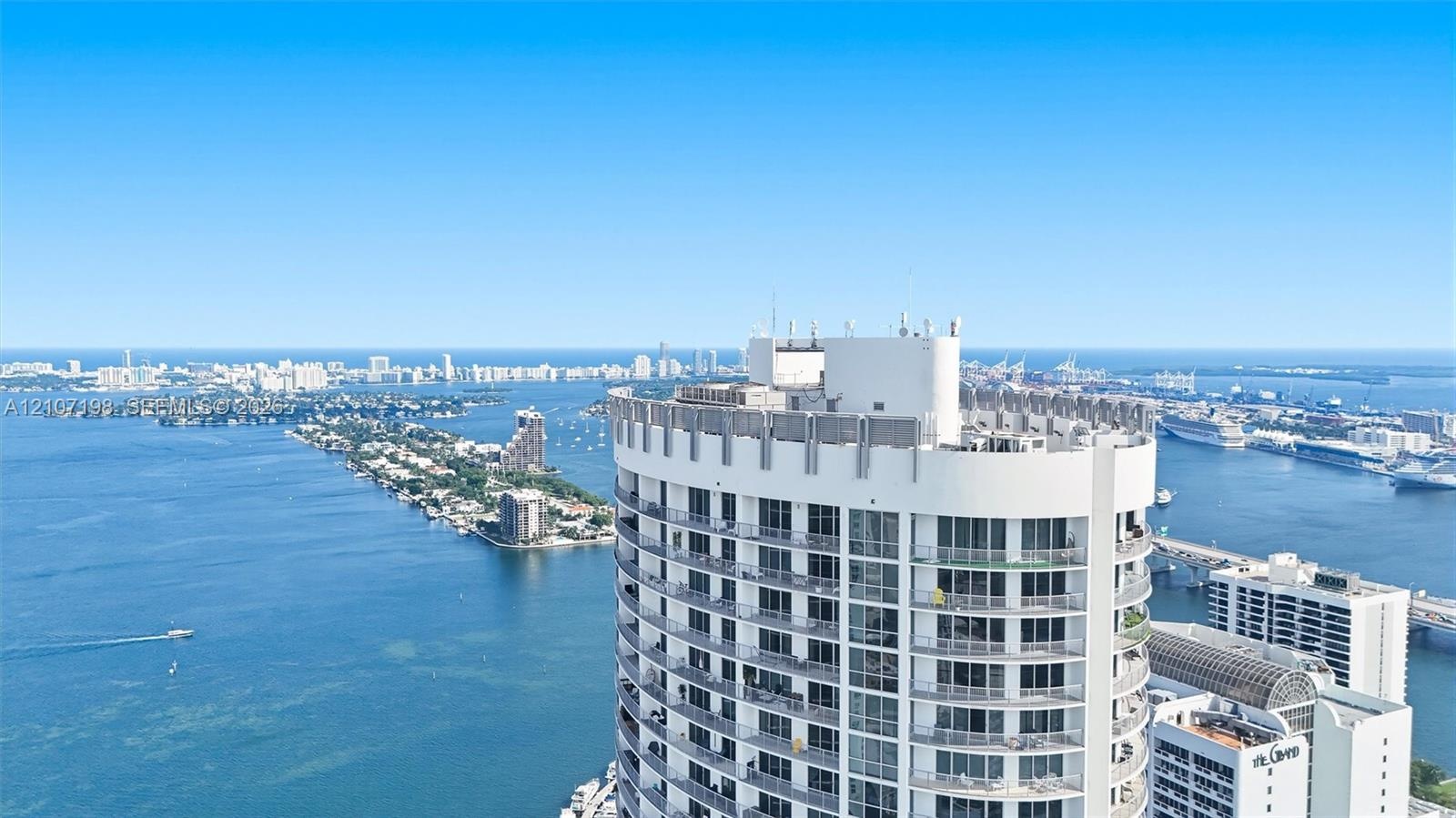 High-rise building featuring a curved architectural design, floor-to-ceiling glass windows, and private balconies overlooking the surrounding bay and 