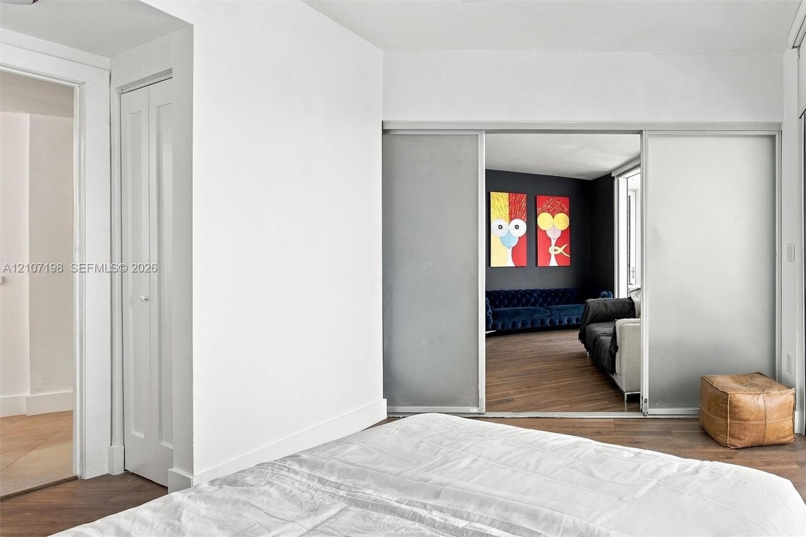 Wood-finish flooring, sliding frosted glass panel doors, and floor-to-ceiling bi-fold closet doors