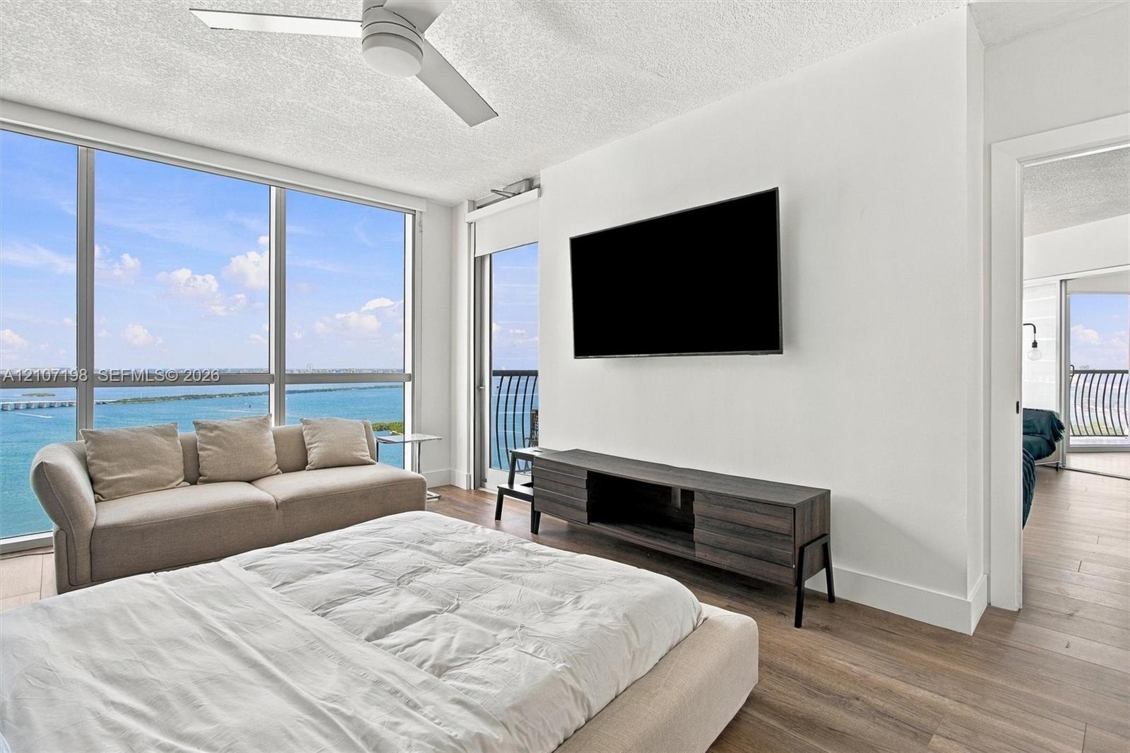 Floor-to-ceiling windows, wood-finish flooring, ceiling fan, and balcony access