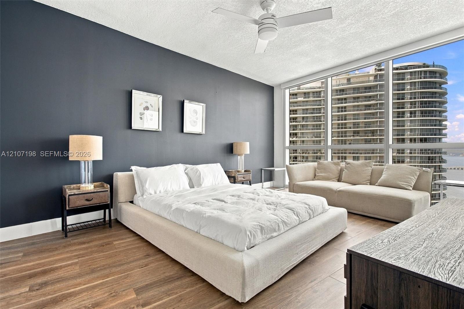 Floor-to-ceiling windows, wood-finish flooring, accent wall, and ceiling-mounted fan