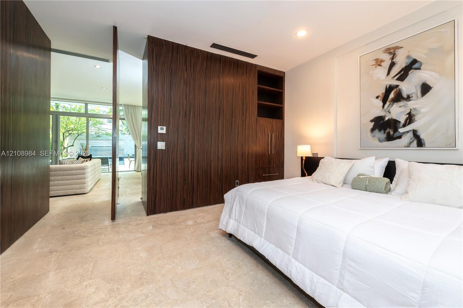 Custom wood-paneled wall with integrated built-in cabinetry, stone flooring, and recessed ceiling lighting