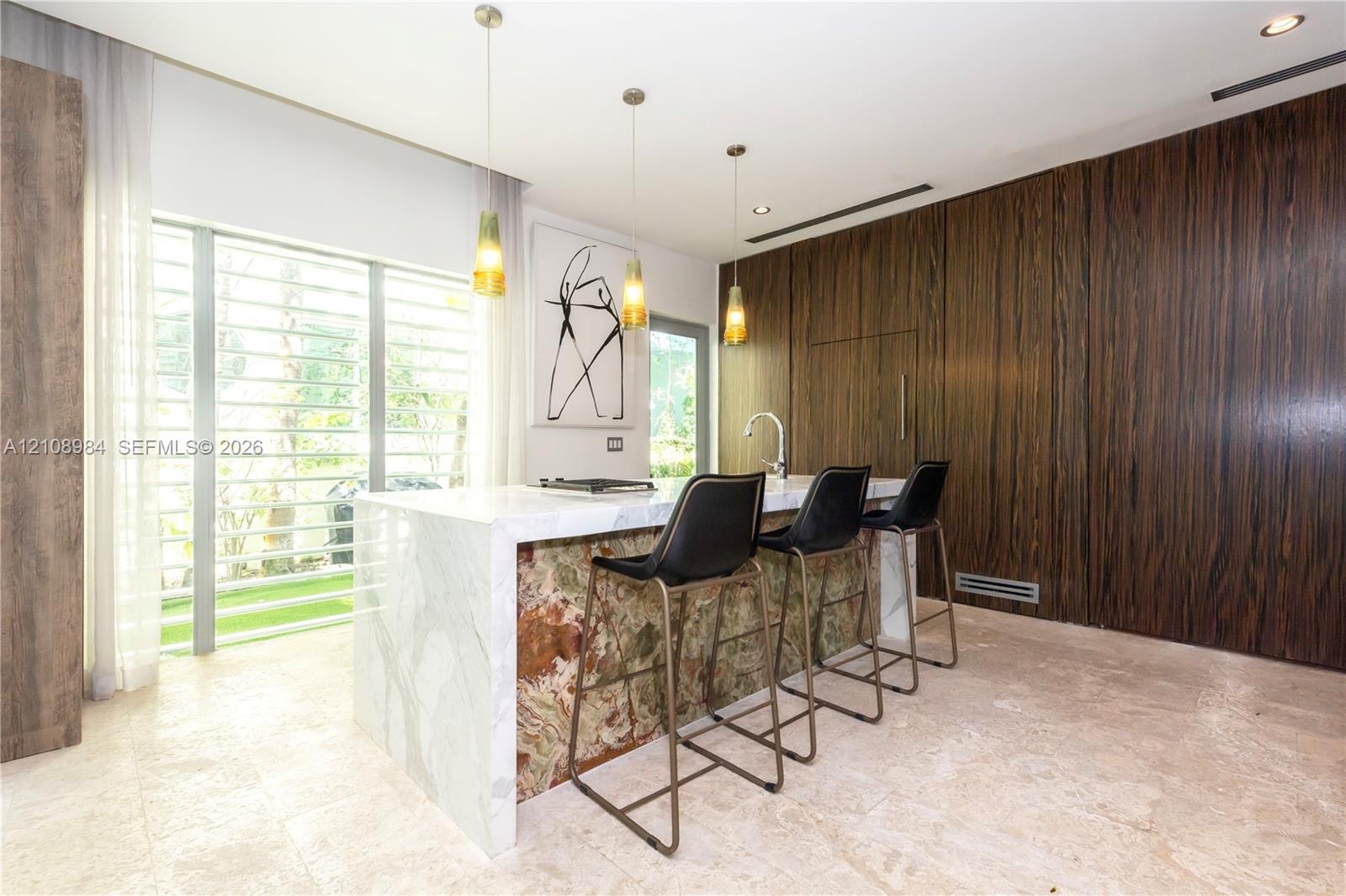 Kitchen island featuring a waterfall stone countertop with a contrasting decorative stone base, floor-to-ceiling wood-finish paneling, stone flooring,