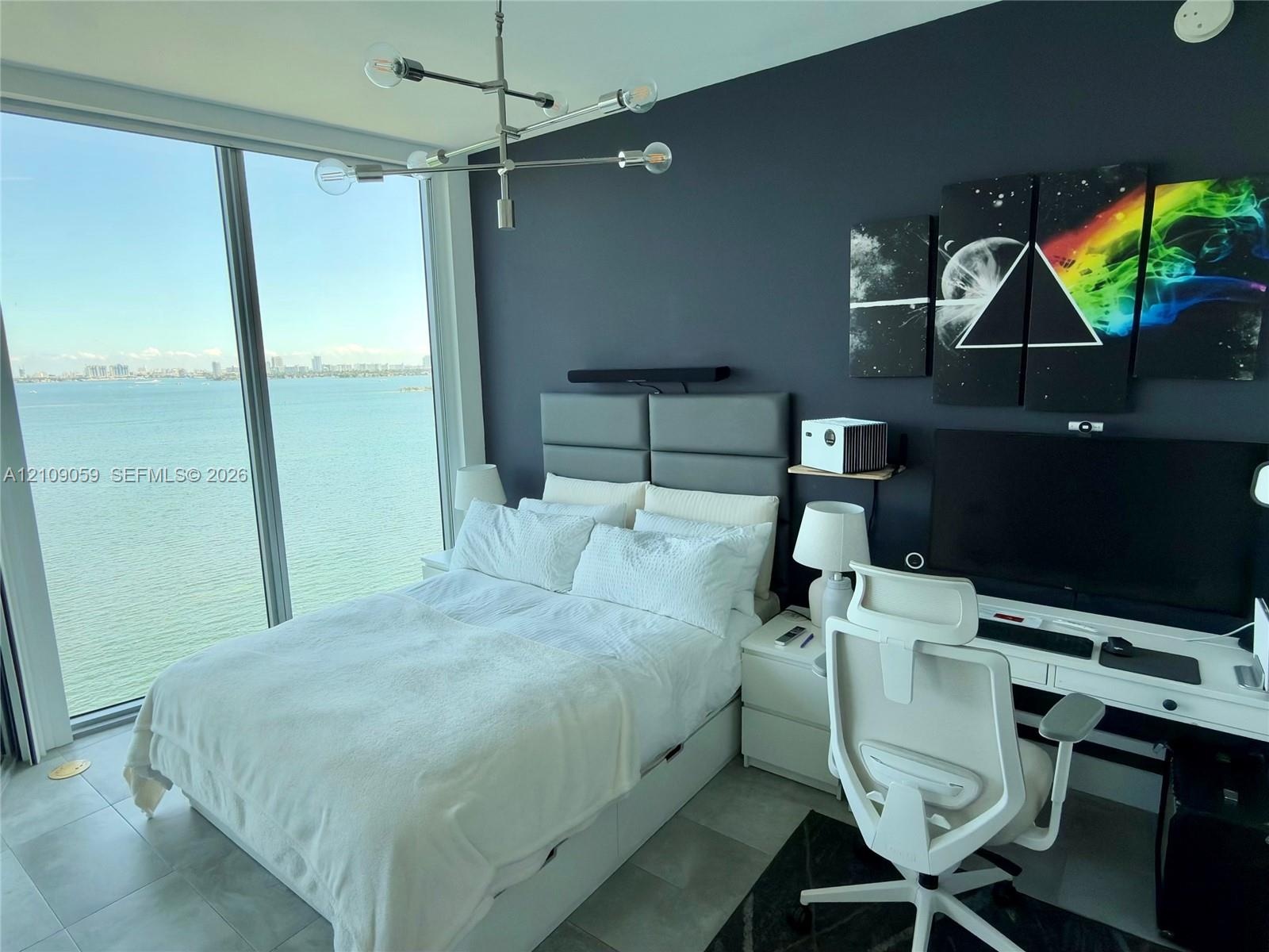 Floor-to-ceiling windows, porcelain tile flooring, modern metal multi-arm chandelier, and accent wall