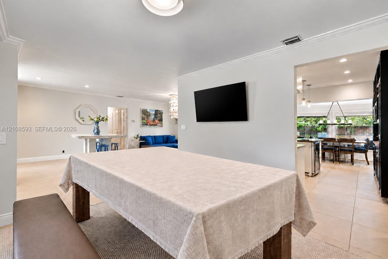 Neutral-toned interior featuring recessed lighting, smooth-finish ceiling, crown molding, and large-format tile flooring