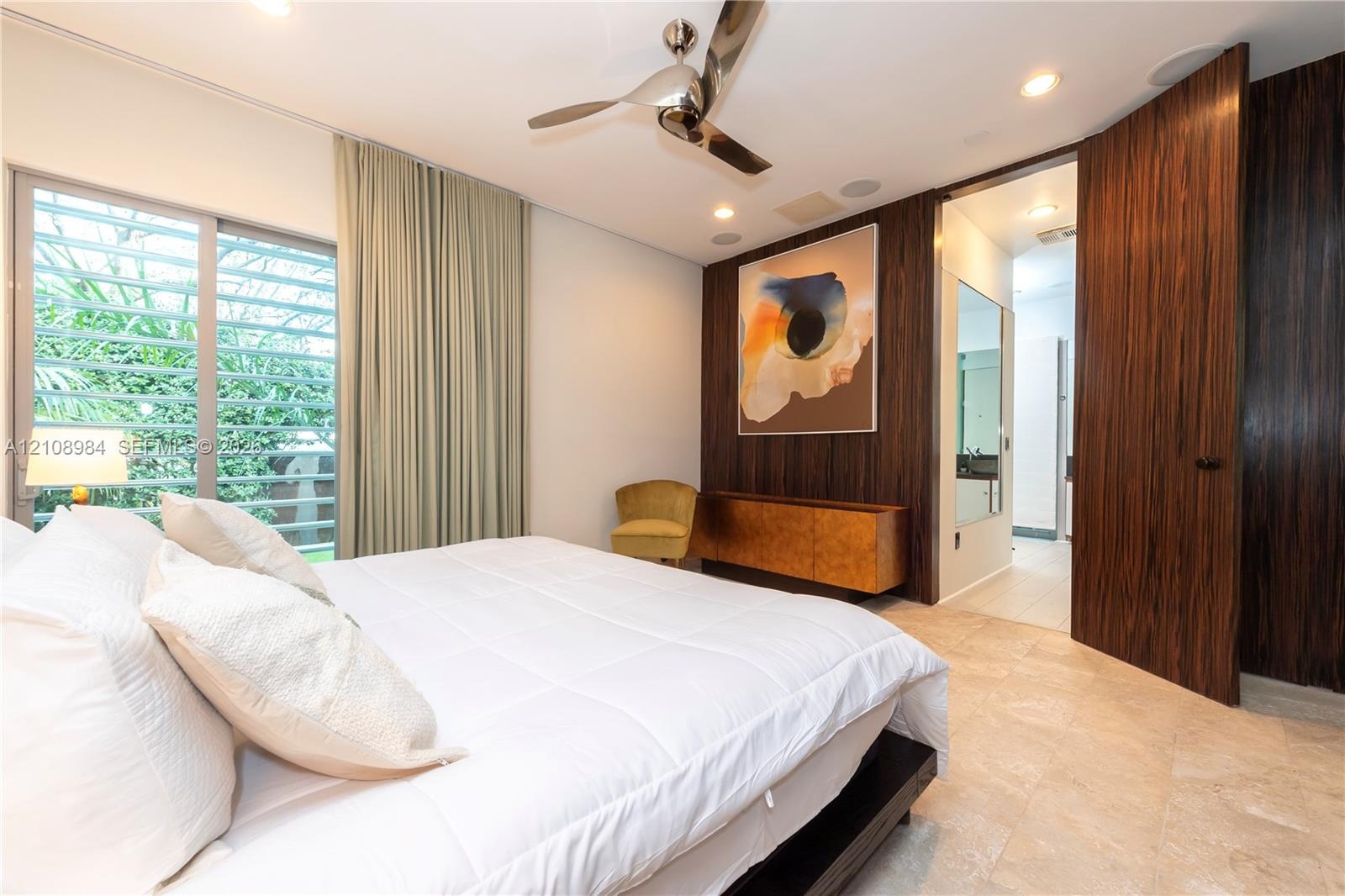 Room featuring natural stone flooring, floor-to-ceiling wood-finish paneling, louvered sliding glass doors, recessed lighting, and a modern metal ceil