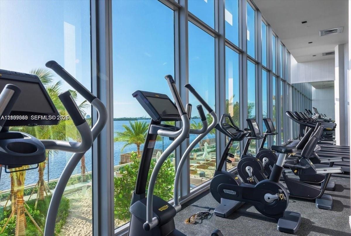 Fitness center featuring floor-to-ceiling windows, extensive water-front exposure, and carpeted flooring