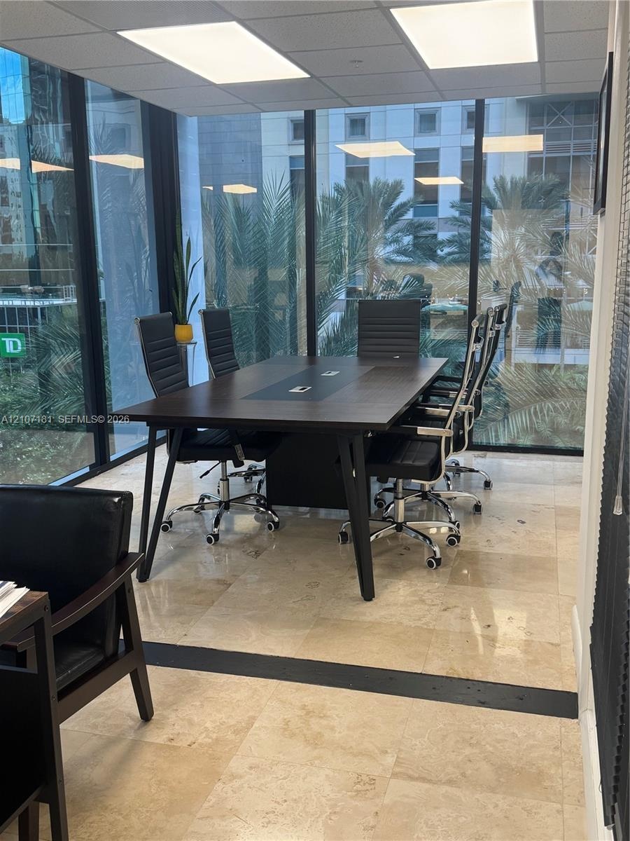 Floor-to-ceiling glass walls, polished stone flooring, recessed ceiling lighting, and integrated dark-finish built-in conference table