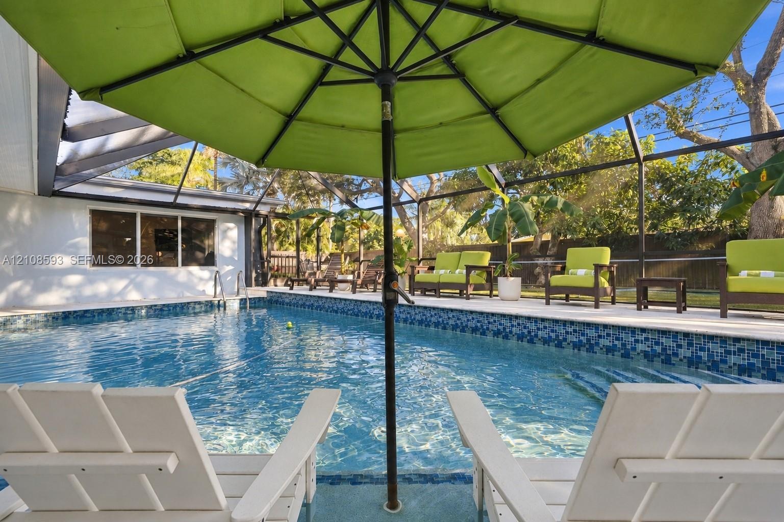 Screened-in patio area featuring a swimming pool with blue mosaic tile perimeter and concrete pool deck