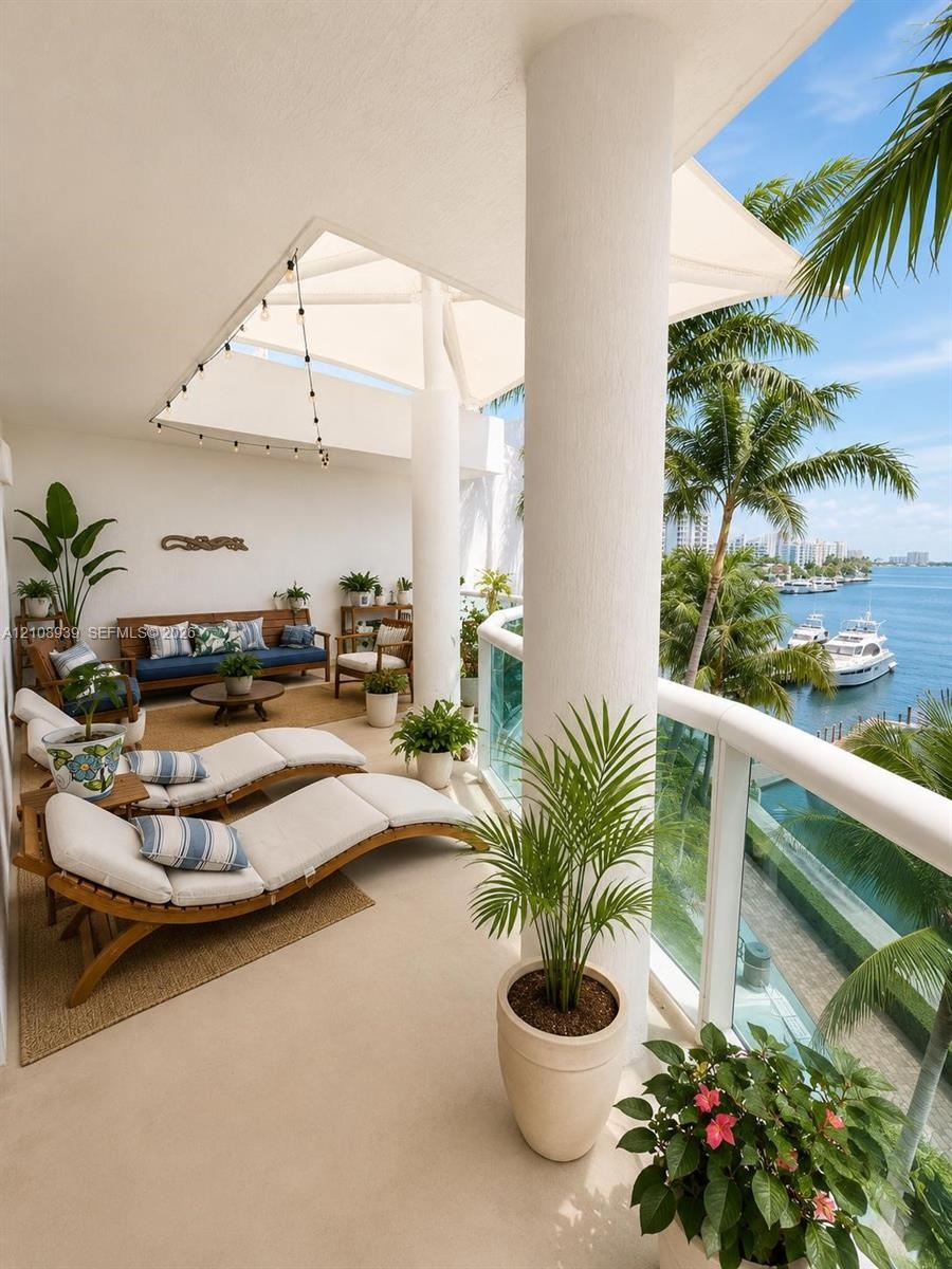 Covered terrace featuring structural columns, neutral-toned flooring, and a glass-paneled railing overlooking the waterfront
