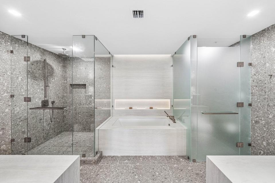 A luxurious spa-like sanctuary showcasing sleek contemporary cabinetry, expansive mirrors, a freestanding soaking tub, and beautifully coordinated des
