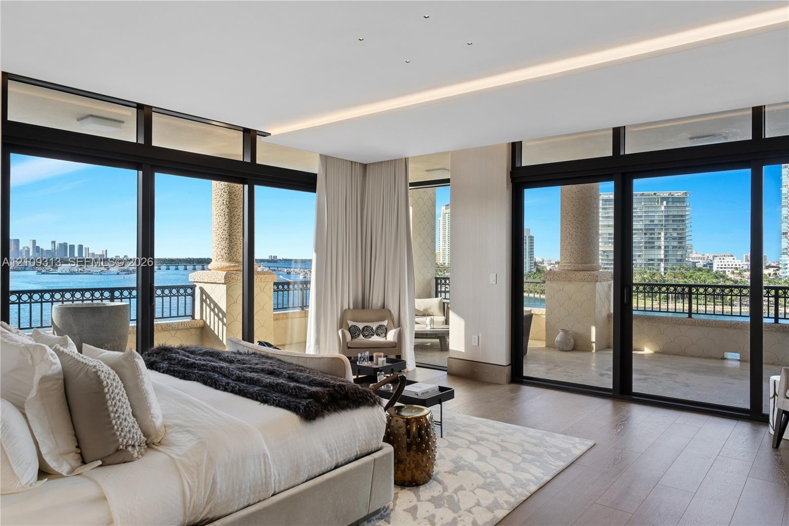 Floor-to-ceiling glass walls, integrated cove lighting, wood-finish flooring, and a wrap-around balcony with stone columns