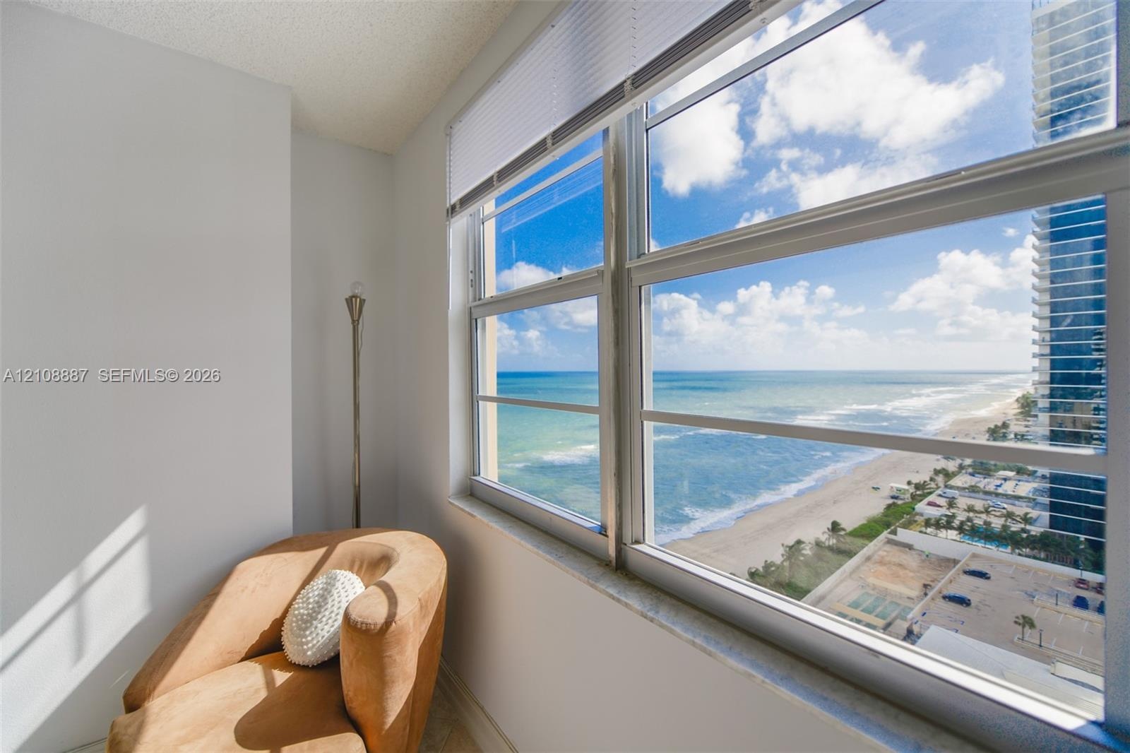 Large-pane windows with horizontal blinds featuring a direct perspective of the ocean and shoreline