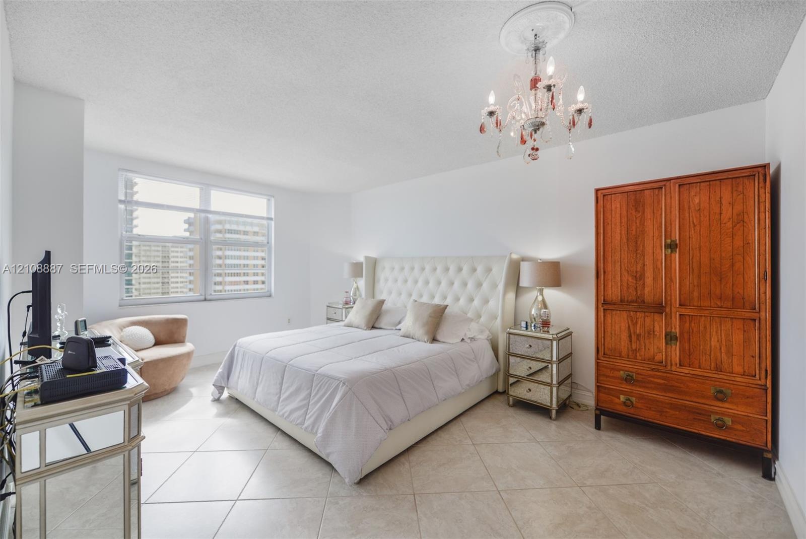 Bedroom featuring large windows, neutral tile flooring, and a decorative ceiling-mounted chandelier