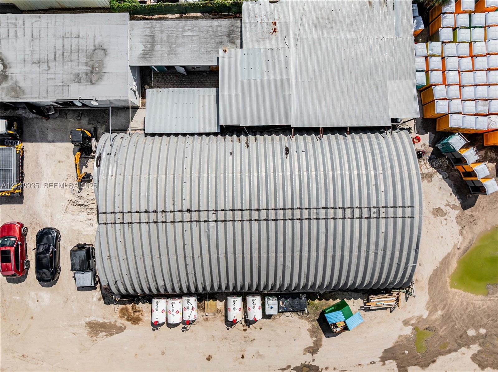 Quonset hut structure featuring a corrugated metal roof and expansive open-air ground space