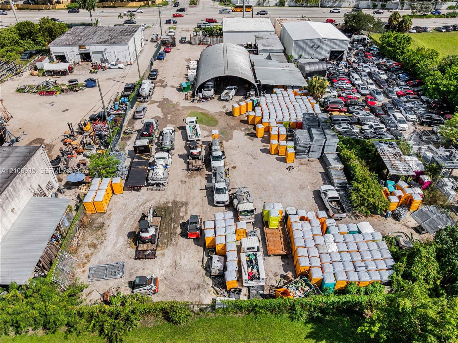 Industrial property featuring a metal-framed arched warehouse structure, expansive open-air storage yard, and perimeter fencing