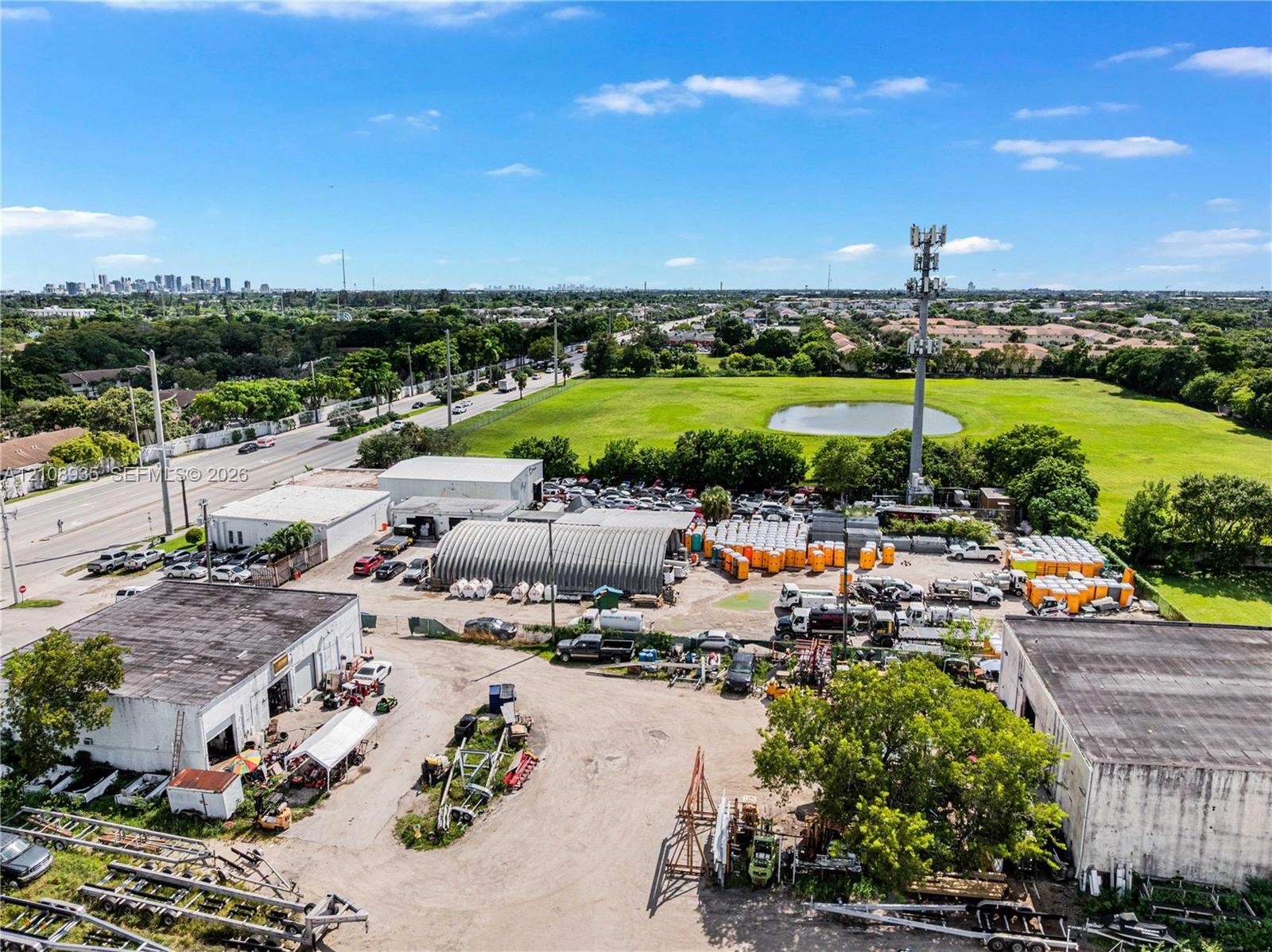 Expansive industrial property featuring multiple detached structures, a metal Quonset-style building, dedicated paved and unpaved storage areas, and d