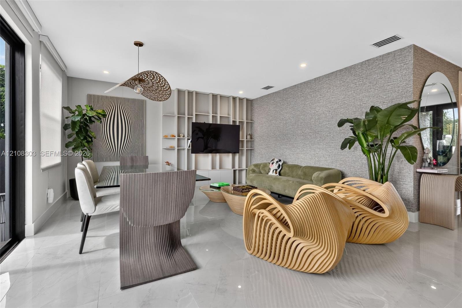 Open-concept living space featuring high-gloss tile flooring, custom floor-to-ceiling built-in shelving, textured wall treatment, and recessed lightin