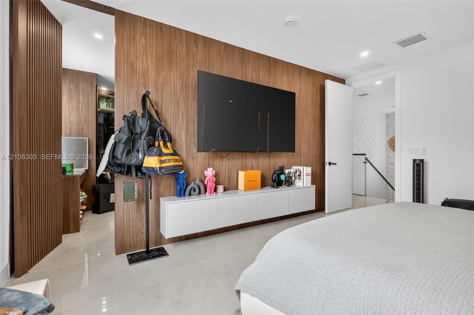 Custom wood-panel accent wall featuring a wall-mounted matte white floating credenza, recessed lighting, and large-format tile flooring