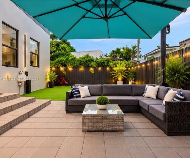 Outdoor patio featuring large-format concrete pavers, tiered stone steps, and a perimeter privacy fence with integrated string lighting