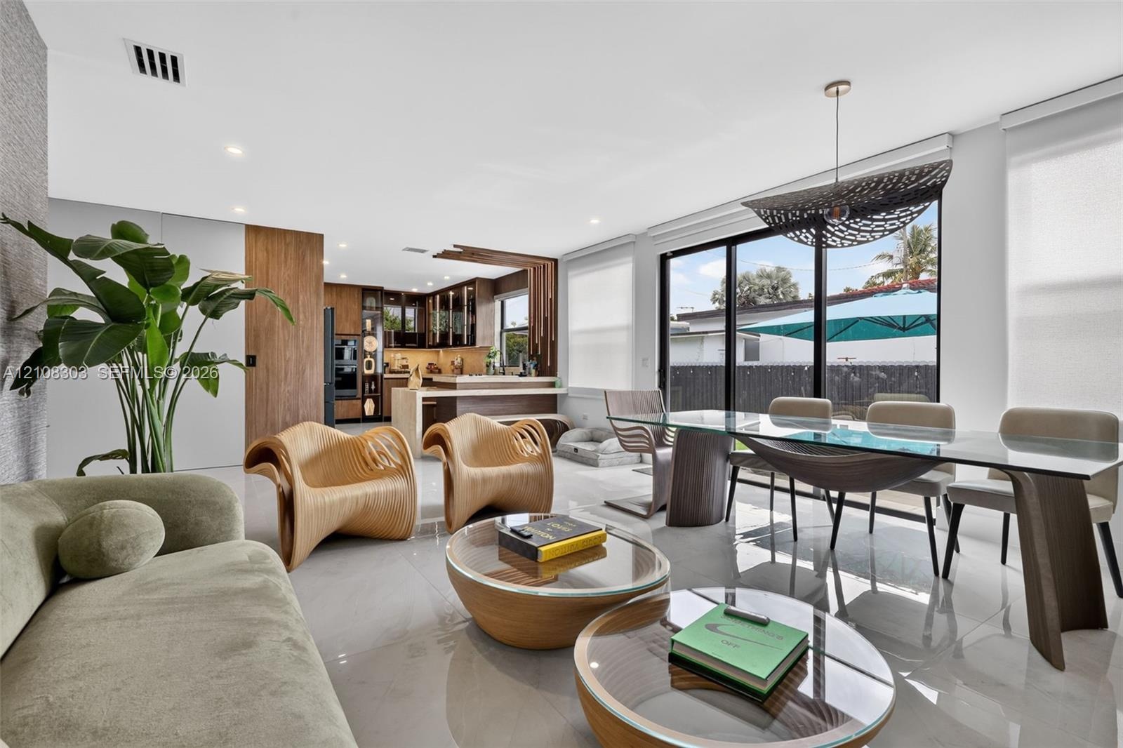 Open-concept interior featuring large-format tile flooring, recessed lighting, wood-finish cabinetry, and sliding glass doors with exterior access