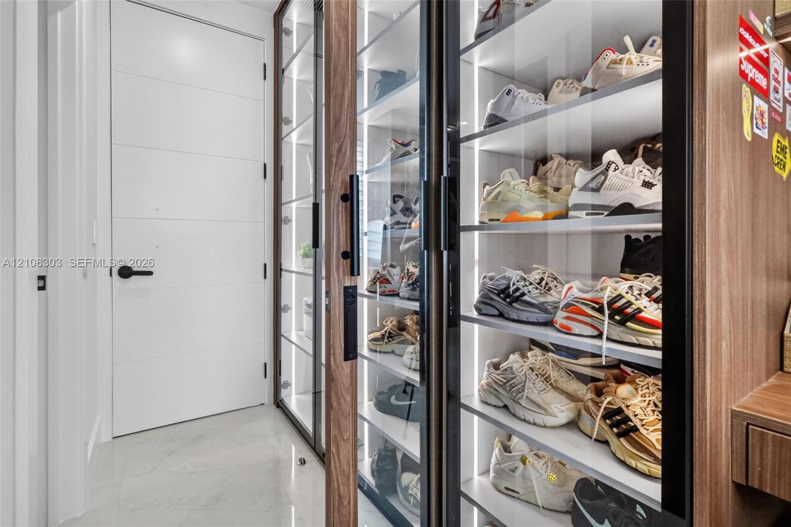 Built-in floor-to-ceiling cabinetry with glass-panel doors, integrated vertical LED strip lighting, wood-finish shelving, and matte black hardware, fe