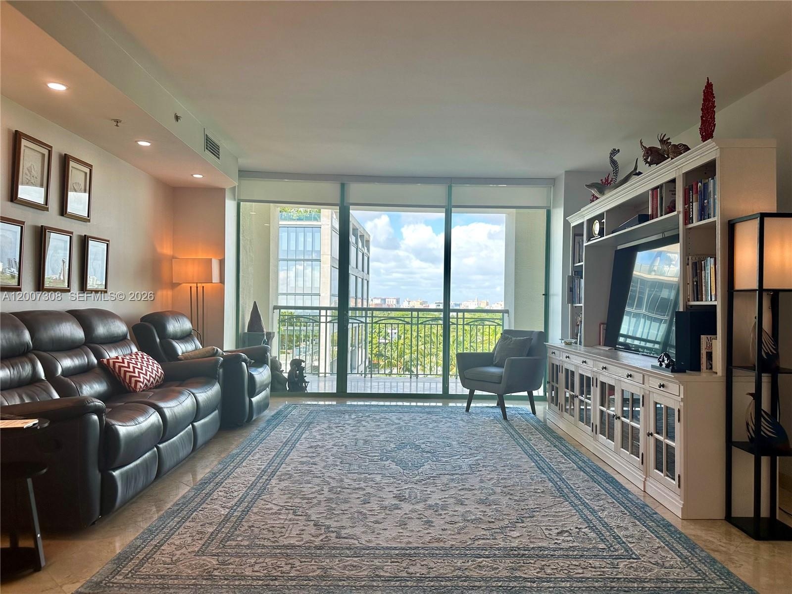 Living area featuring floor-to-ceiling windows, built-in cabinetry, recessed lighting, and a balcony with an iron railing