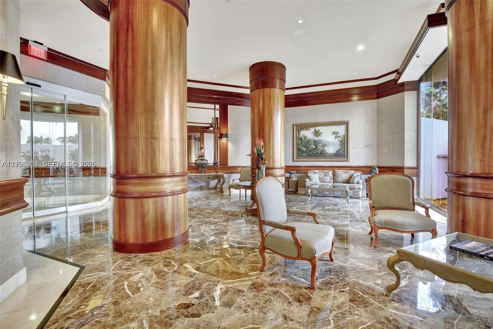 Grand lobby featuring polished stone flooring, floor-to-ceiling wood-finish cylindrical columns, recessed lighting, and crown molding