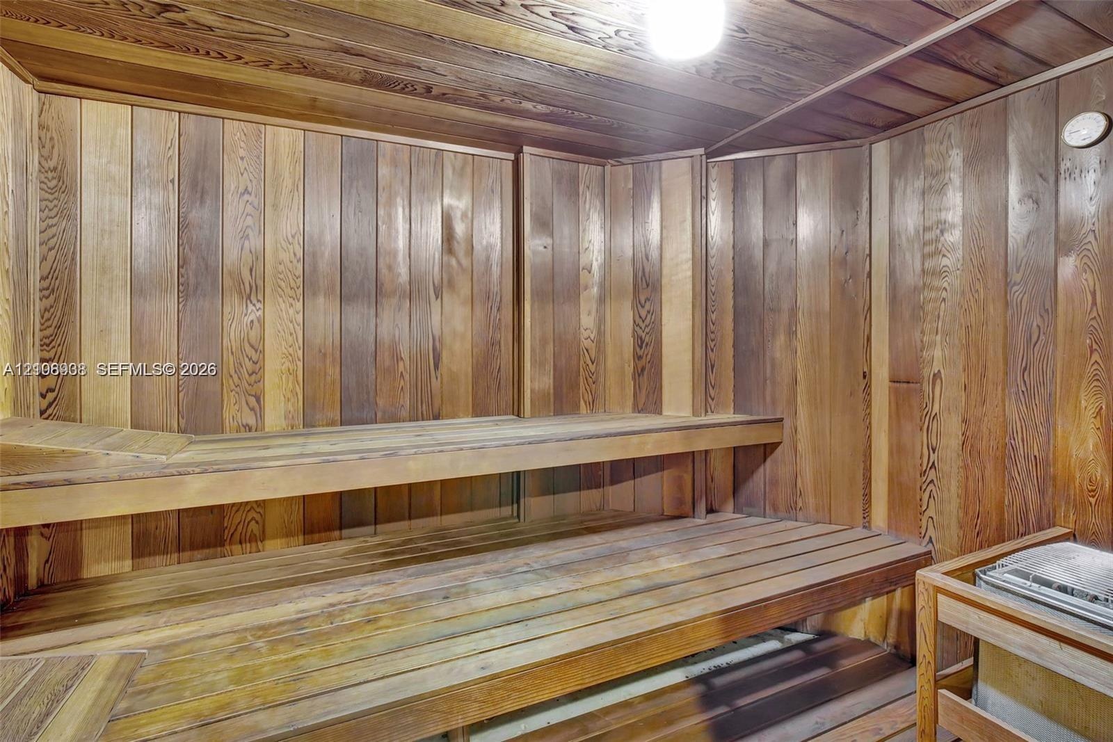 Sauna featuring tongue-and-groove wood paneling, multi-level slatted benches, and a built-in heating unit
