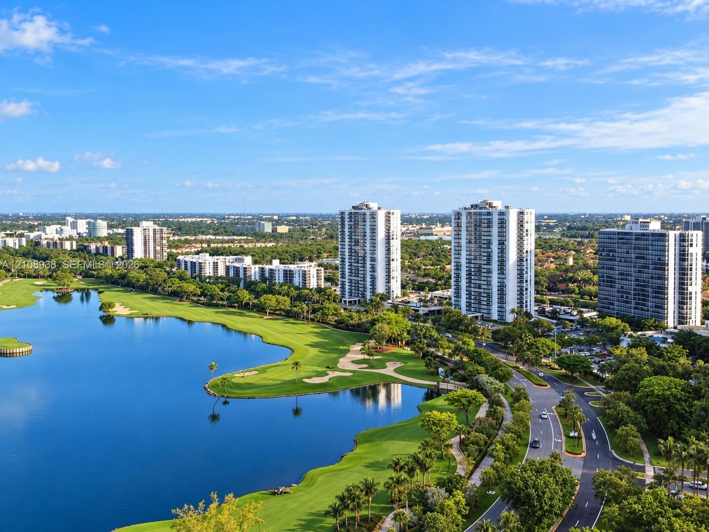 Aerial perspective featuring high-rise residential buildings, expansive landscaped grounds, a large water feature, and maintained turf grass