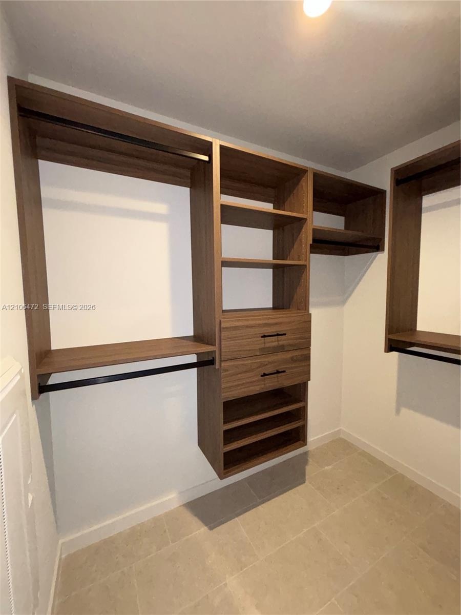 Custom closet organization system featuring wood-finish shelving, integrated drawers with matte black hardware, and dual hanging rods