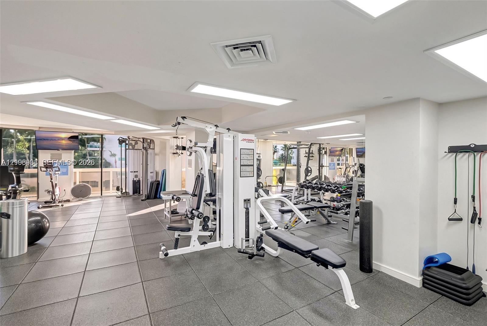 Fitness center featuring large-format tile flooring, recessed panel lighting, and floor-to-ceiling windows