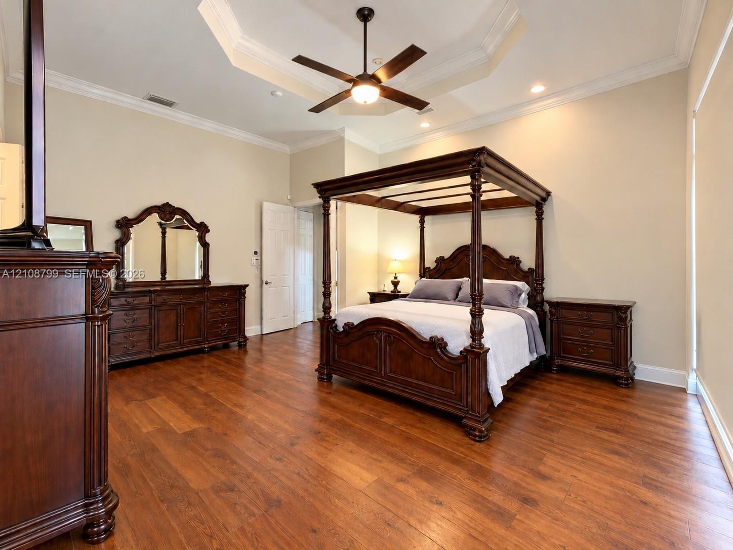 Tray ceiling featuring recessed lighting and a central ceiling fan, complemented by wood-finish flooring