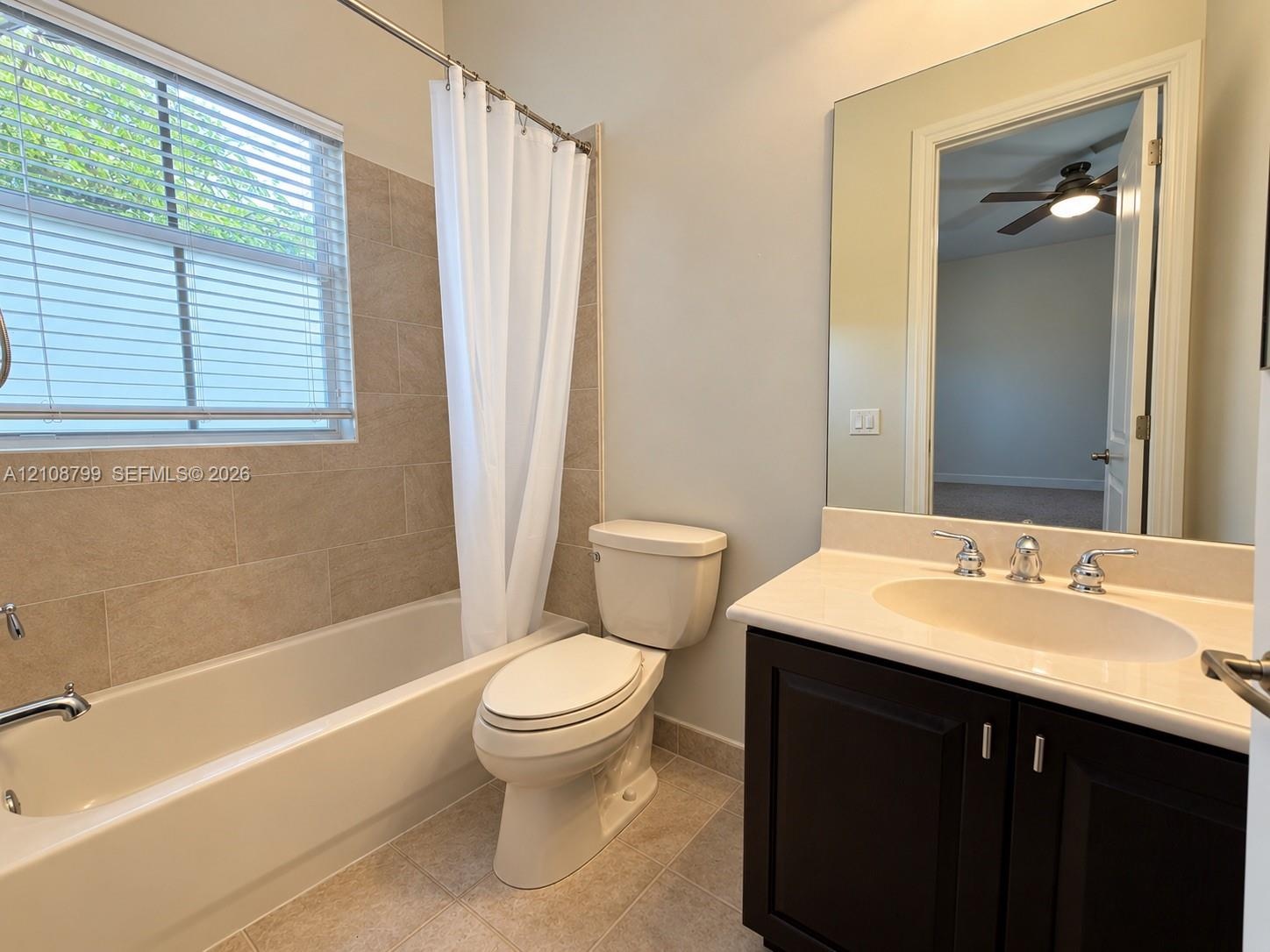 Full bathroom featuring a dark wood-finish vanity with a light-toned countertop, an integrated oval sink, a large wall-mounted mirror, and a tub-showe