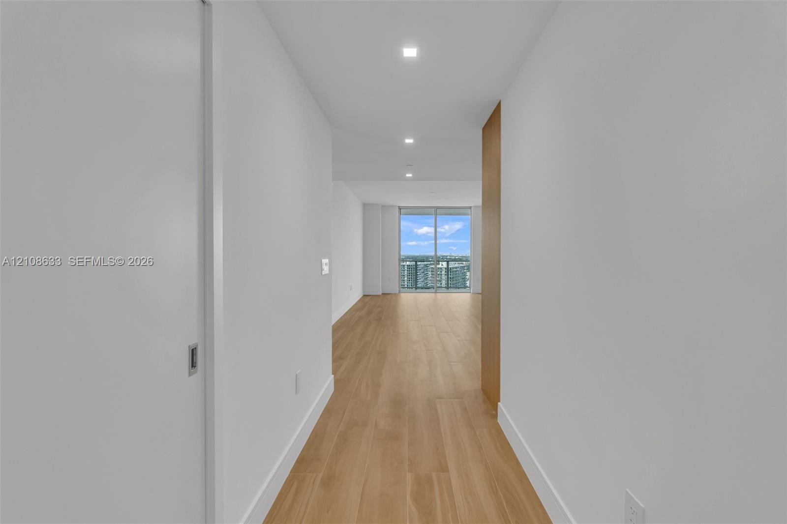 Hallway featuring wood-finish flooring, recessed lighting, and floor-to-ceiling glass sliding doors