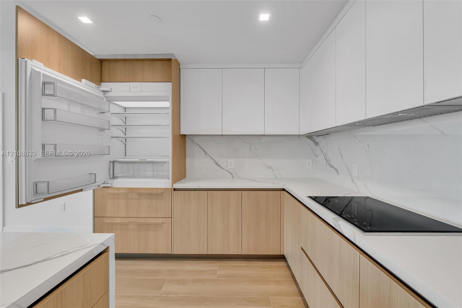 Contemporary kitchen featuring flat-panel wood-finish cabinetry, white matte upper cabinetry, white stone-patterned backsplash, integrated panel-ready
