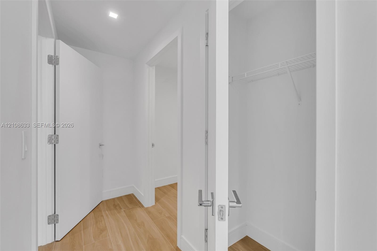 Interior space featuring wood-finish flooring, recessed lighting, and a walk-in closet with built-in wire shelving and modern lever-handle hardware