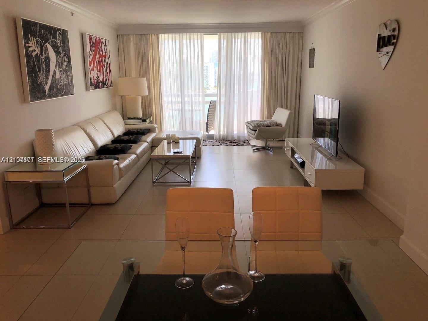 Open-concept interior featuring large-format tile flooring, crown molding, and floor-to-ceiling glass paneling