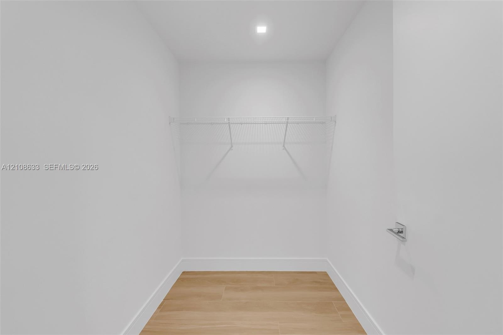 Storage space featuring wood-finish flooring, white walls, recessed ceiling lighting, and built-in wire shelving