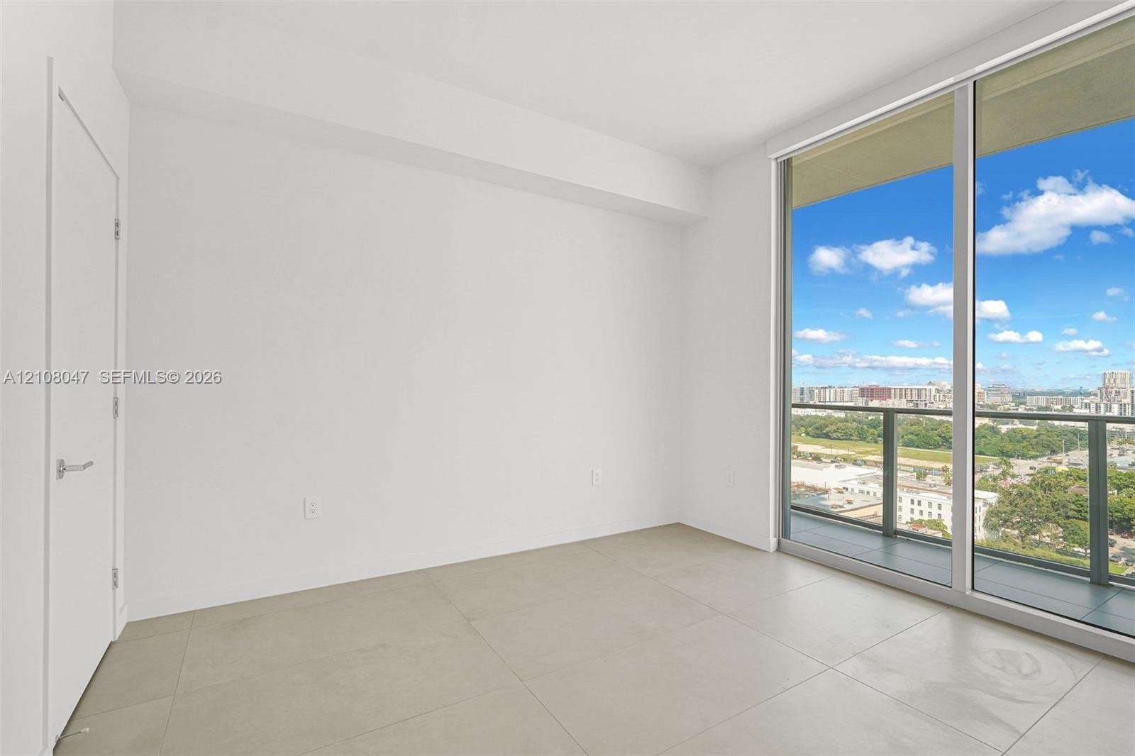 Expansive sliding glass doors, contemporary tile flooring, and a clean white color palette create a bright, open interior