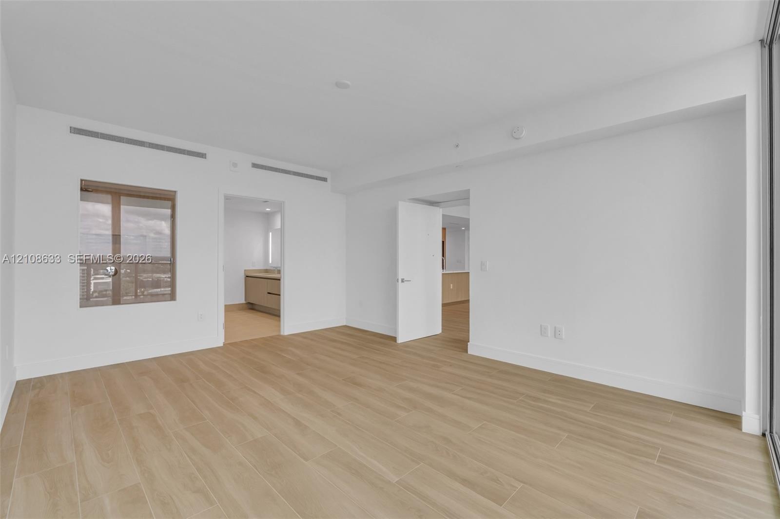 Interior space featuring wood-finish flooring, white walls, and a large window