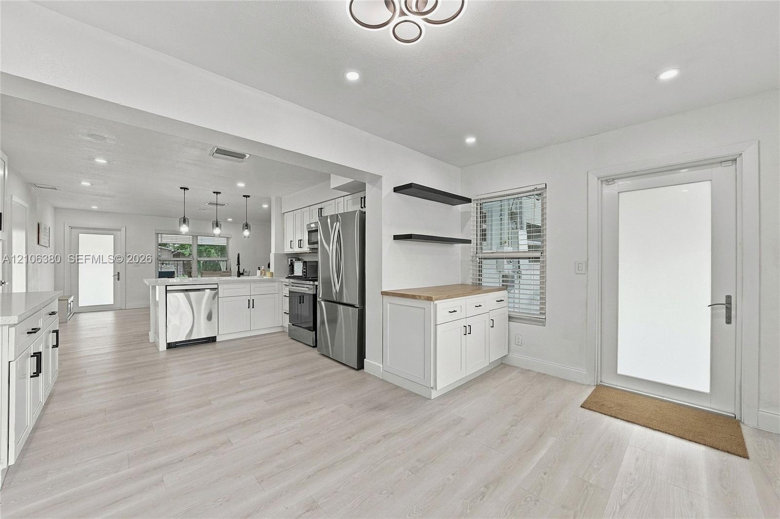 Kitchen featuring white cabinetry, stainless steel appliances, wood-finish flooring, recessed lighting, and a butcher-block countertop workspace with 