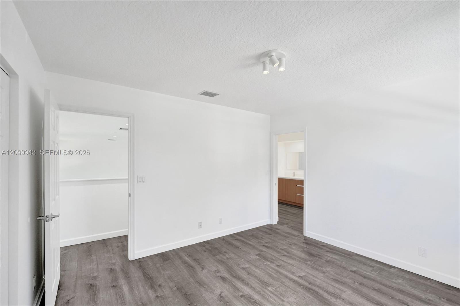 Room featuring wood-finish flooring, white walls, and a multi-directional ceiling light fixture