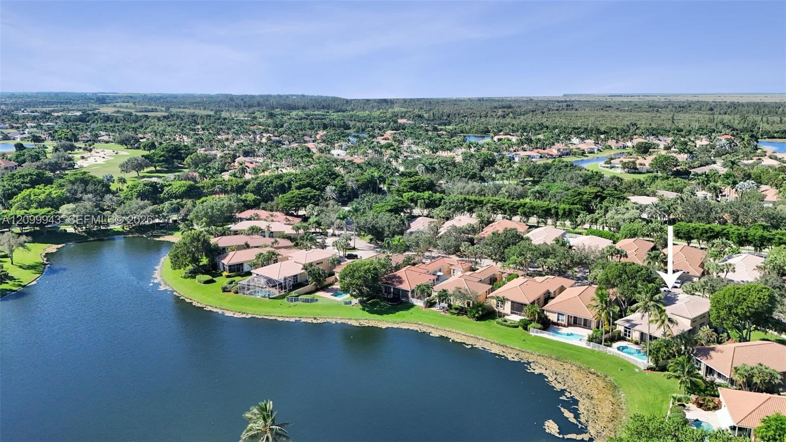 Aerial perspective showcasing a residential property featuring a tiled roof, a private swimming pool, and direct water frontage, situated within a lan