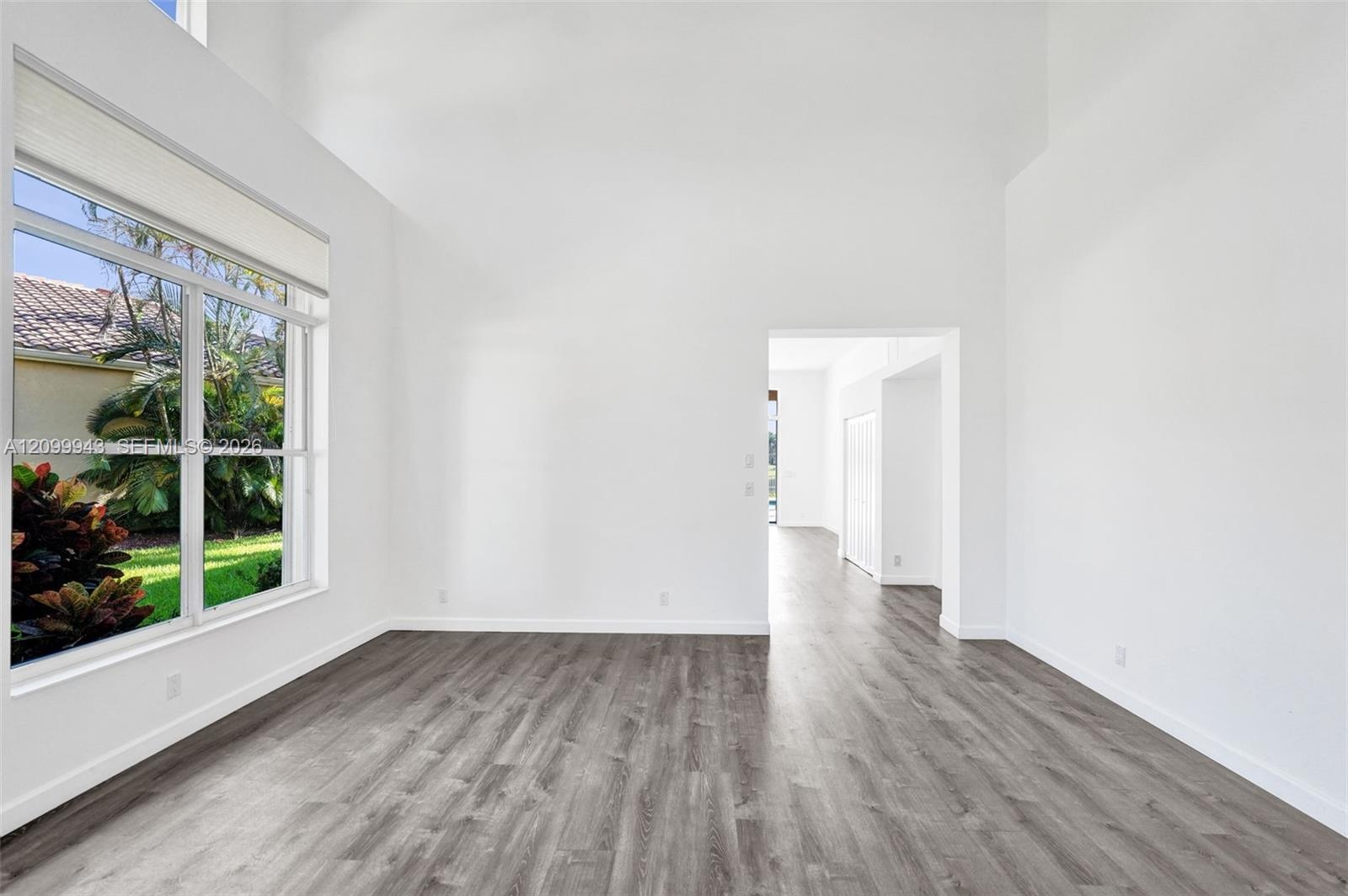 Room featuring high vaulted ceilings, expansive multi-pane window, and wood-finish flooring