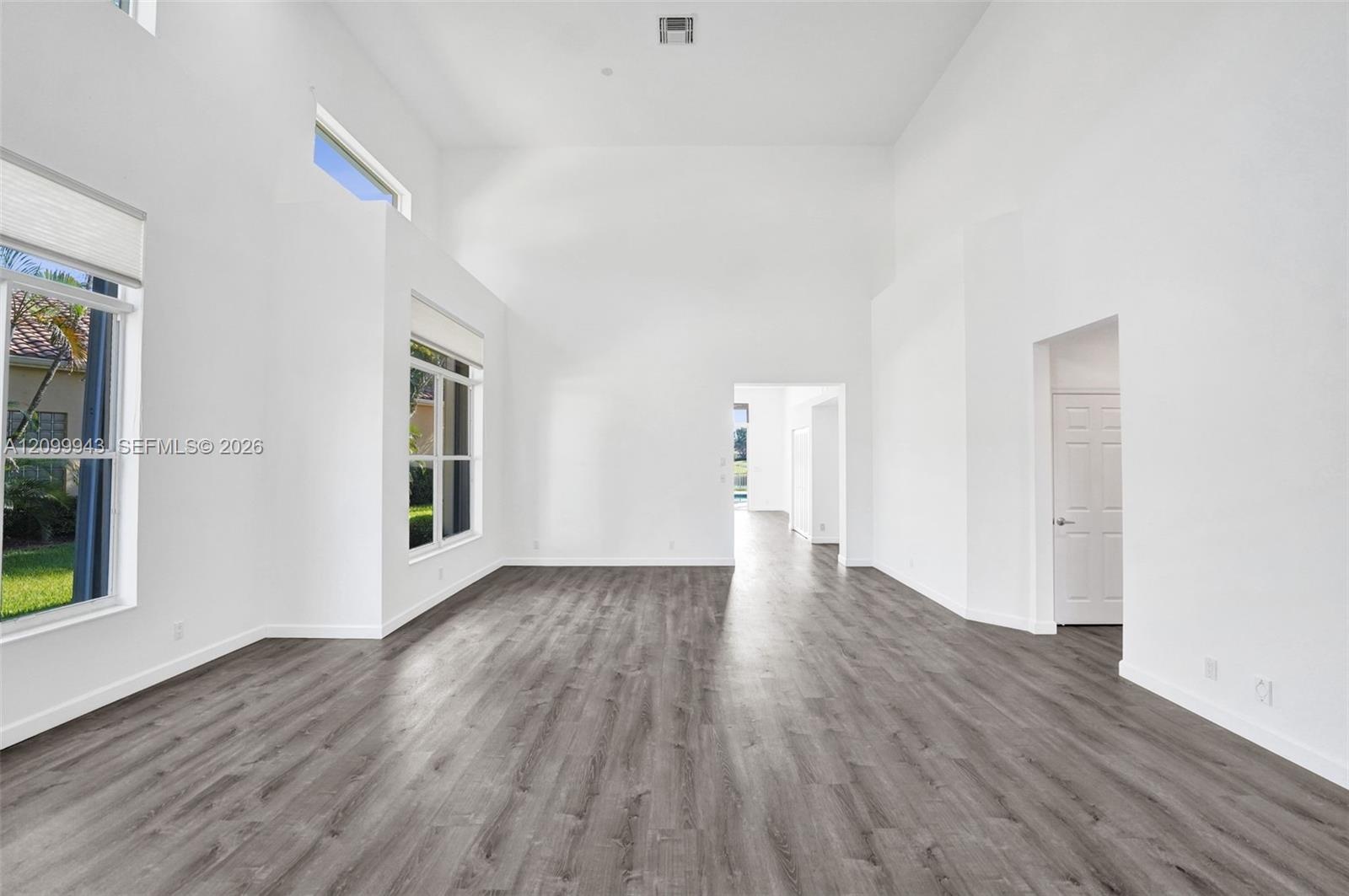 Interior space with high ceilings, wood-finish flooring, and expansive windows providing natural light